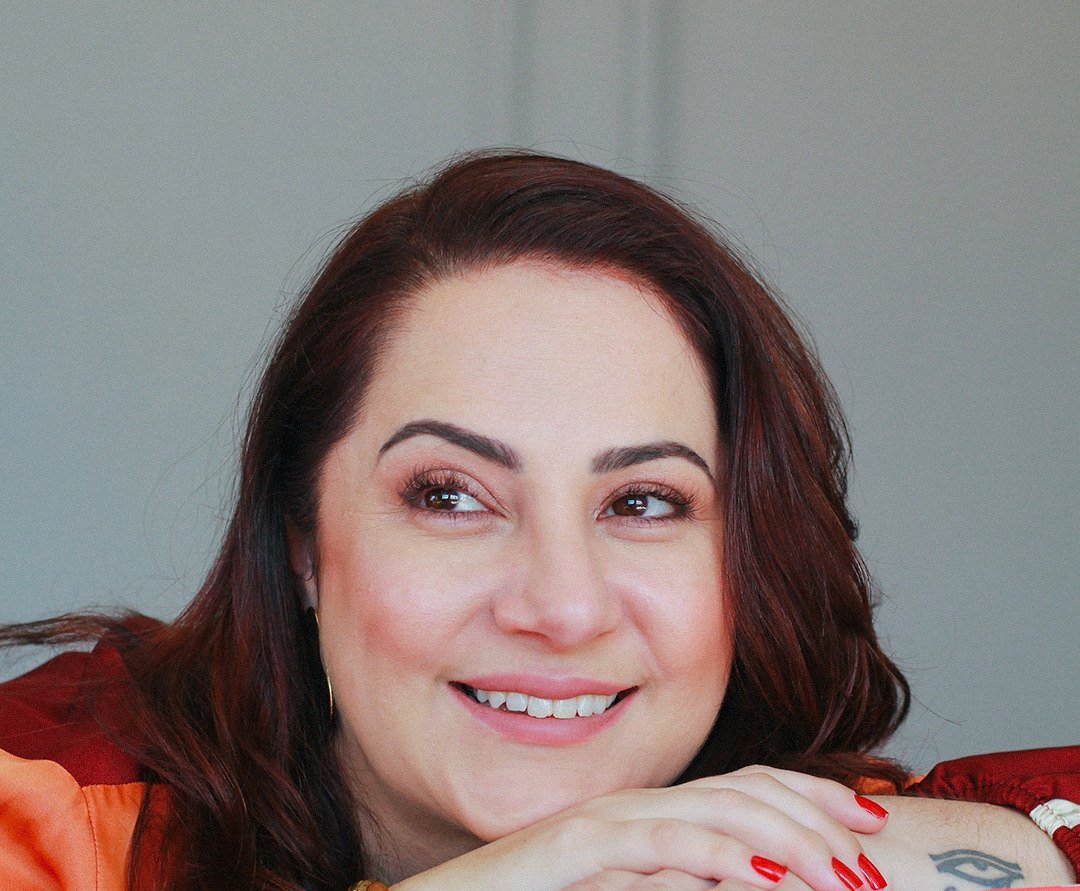 Retrato de Fernnanda Pelissoni sorrindo, com o rosto apoiado nas mãos
