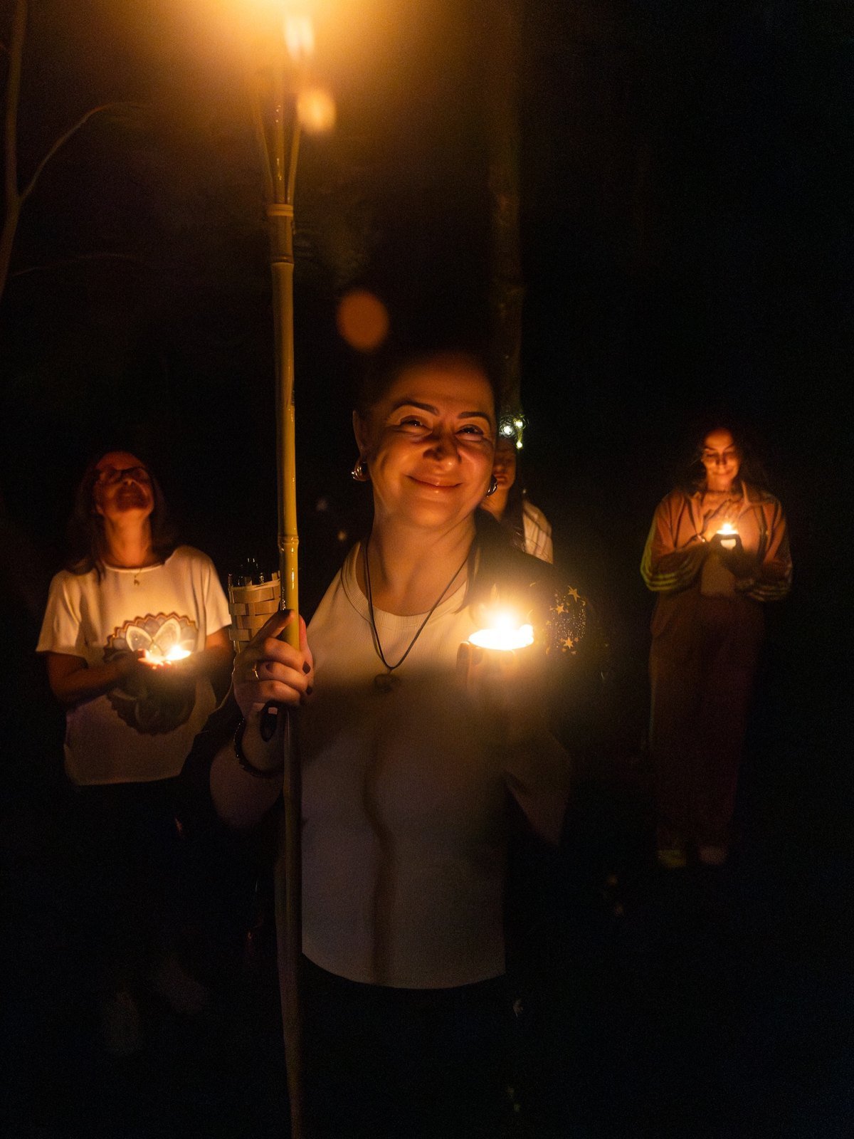 Mulheres à noite segurando tochas e velas acesas durante o retiro